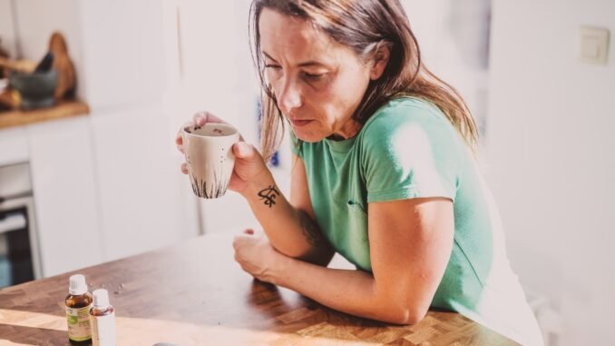 Woman holding a mug, contemplating sobriety, alcohol-free lifestyle, Deep Sober recovery support.
