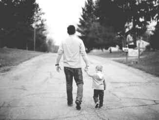 Man walking with young boy on street, supporting sobriety, fatherhood, and healthy lifestyle.