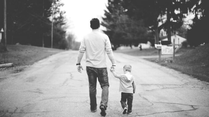 Man walking with young boy on street, supporting sobriety, fatherhood, and healthy lifestyle.
