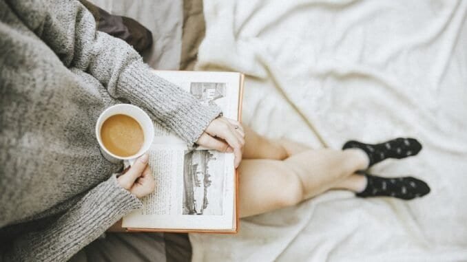 Calm person enjoying coffee and reading a book for sober lifestyle recovery.